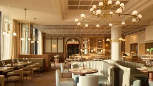 A restaurant with round tables, cushioned seating, and a chandelier. - SLS Barcelona (Sant Adria de Besos)