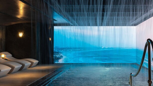 Een wellnessruimte met een groot raam, een jacuzzi en een zithoek.