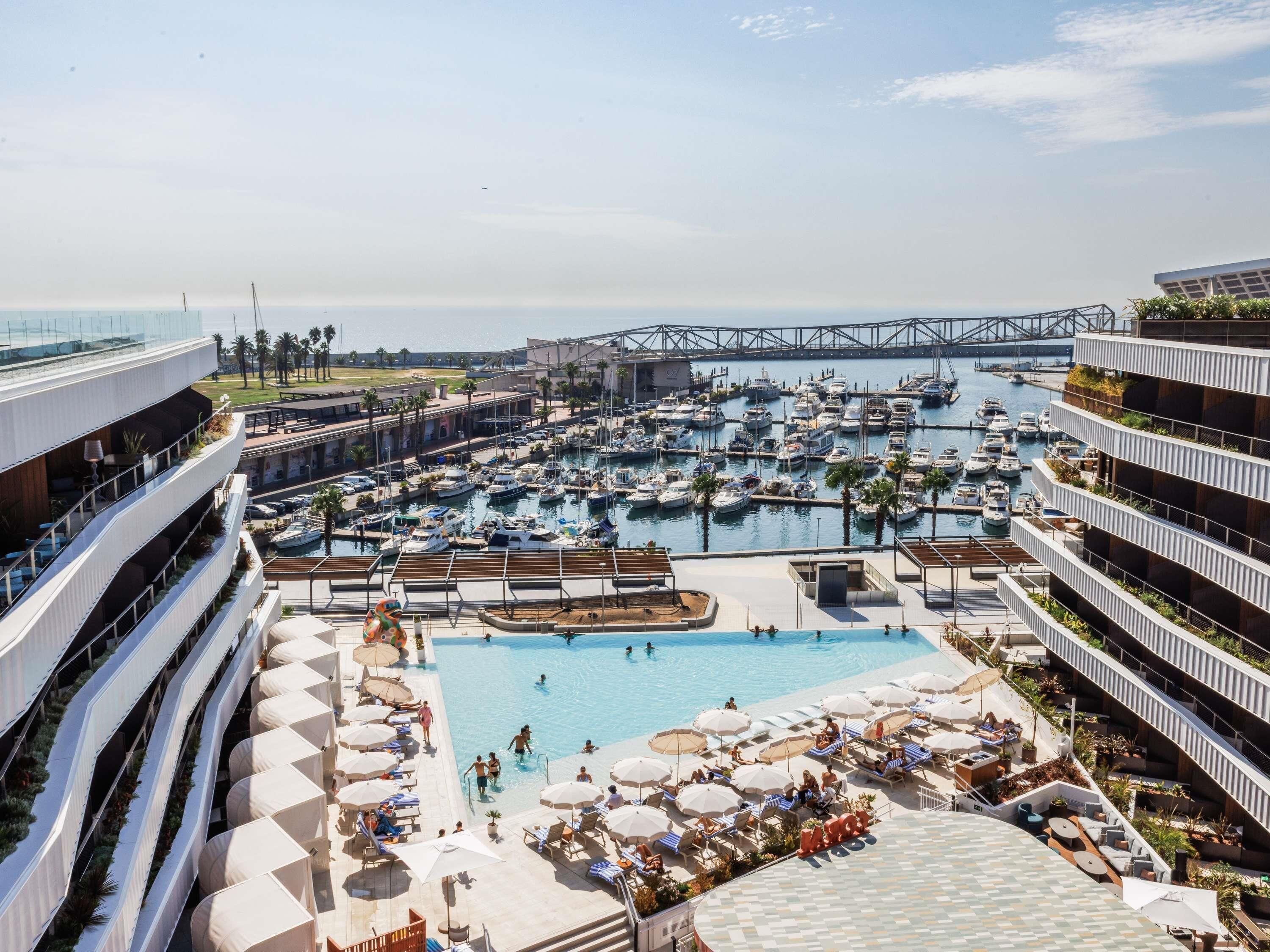 A marina with boats, a swimming pool, and a bridge in the background.