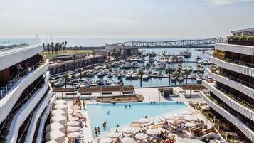 A marina with boats, a swimming pool, and a bridge in the background.