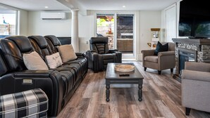 A modern living room with leather sofas, a fireplace, and a large TV. - Lakefront | Hot Tub | 10 Guest | Dock + Kayaks (Seneca Falls)