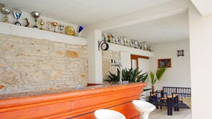 A bar area with a stone wall, a tiled floor, and a seating arrangement with chairs and a table. - Modern Studio apartment "Zara" with private balcony, shared pool (Pula)