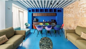 Ein modernes Wohnzimmer mit Essbereich, blauen Wänden, Steindekorationen und einer Küche im Hintergrund.