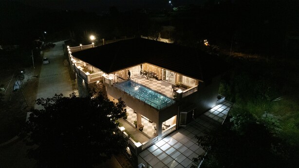 A modern house with a swimming pool, a covered patio, and a well-lit interior.