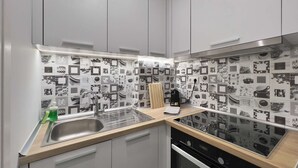 A modern kitchen with white cabinets, a stainless steel sink, and a black dishwasher. - Éclair: Lovely 2BD apt perfect for families (Thessaloniki)