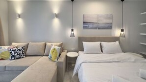 Una habitación de hotel moderna con un sofá, dos camas, una mesita redonda y un cuadro en la pared.