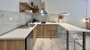 Eine moderne Küche mit Marmorarbeitsplatten, Holzschränken und einer Kochinsel in der Mitte.