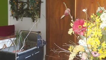 Una habitación con un armario de madera, un carrito pequeño con plantas y un adorno floral en la pared.
