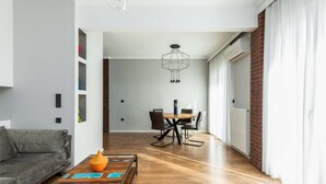 A modern living room with a grey sofa, a wooden coffee table, and a dining area with a table and chairs. - Estelle: Grand 2-BD + 2 bath center apt (Thessaloniki)
