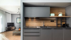 A modern kitchen with a dark grey cabinetry, a wooden backsplash, and a built-in oven. - Estelle: Grand 2-BD + 2 bath center apt (Thessaloniki)
