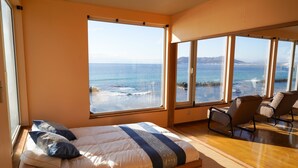 A bedroom with a large bed, two chairs, and a view of the ocean. - Nesaki Native (Hakodate)