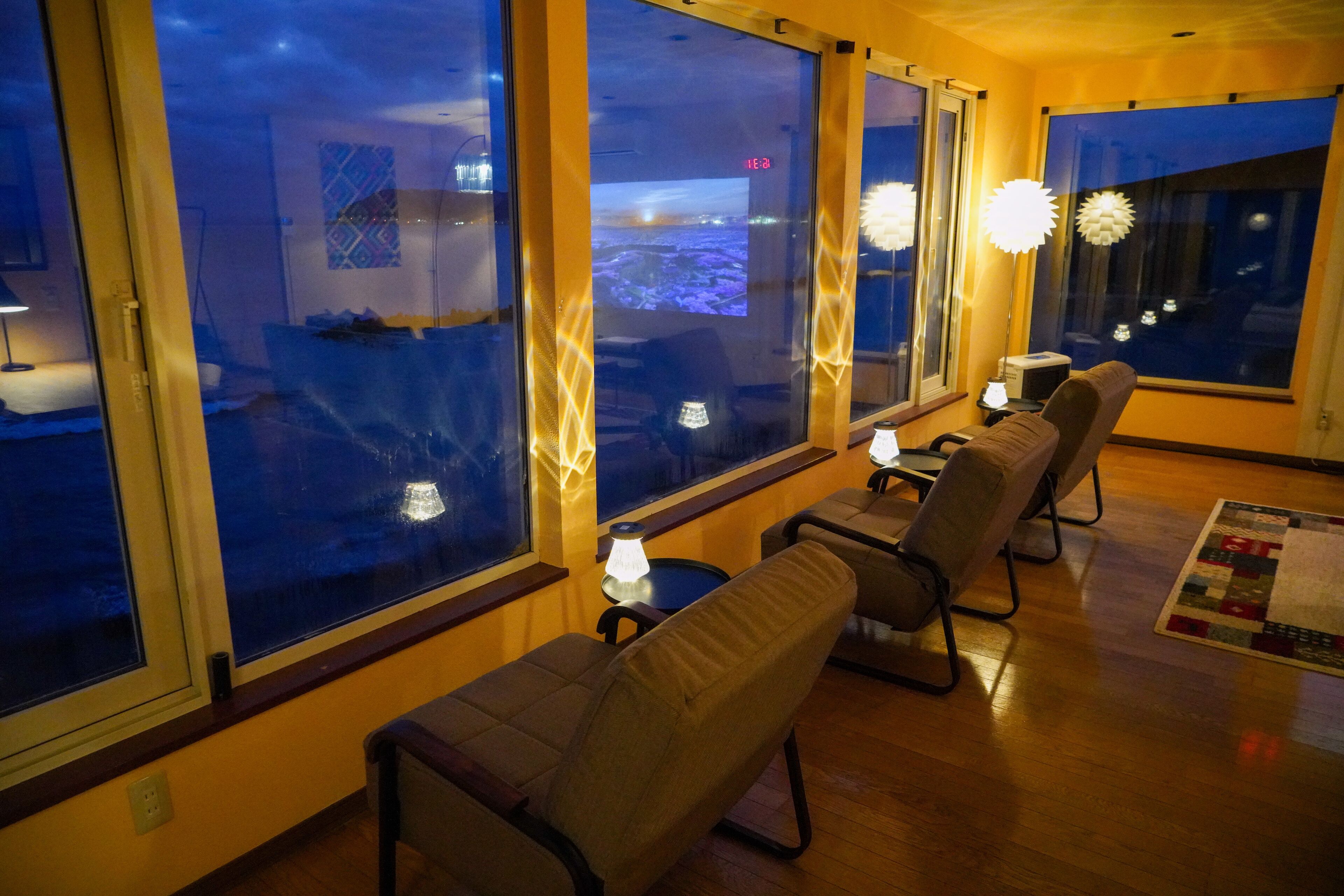 A cozy room with large windows, a view of the cityscape, and comfortable seating.