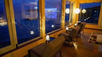 A cozy room with large windows, a view of the cityscape, and comfortable seating.