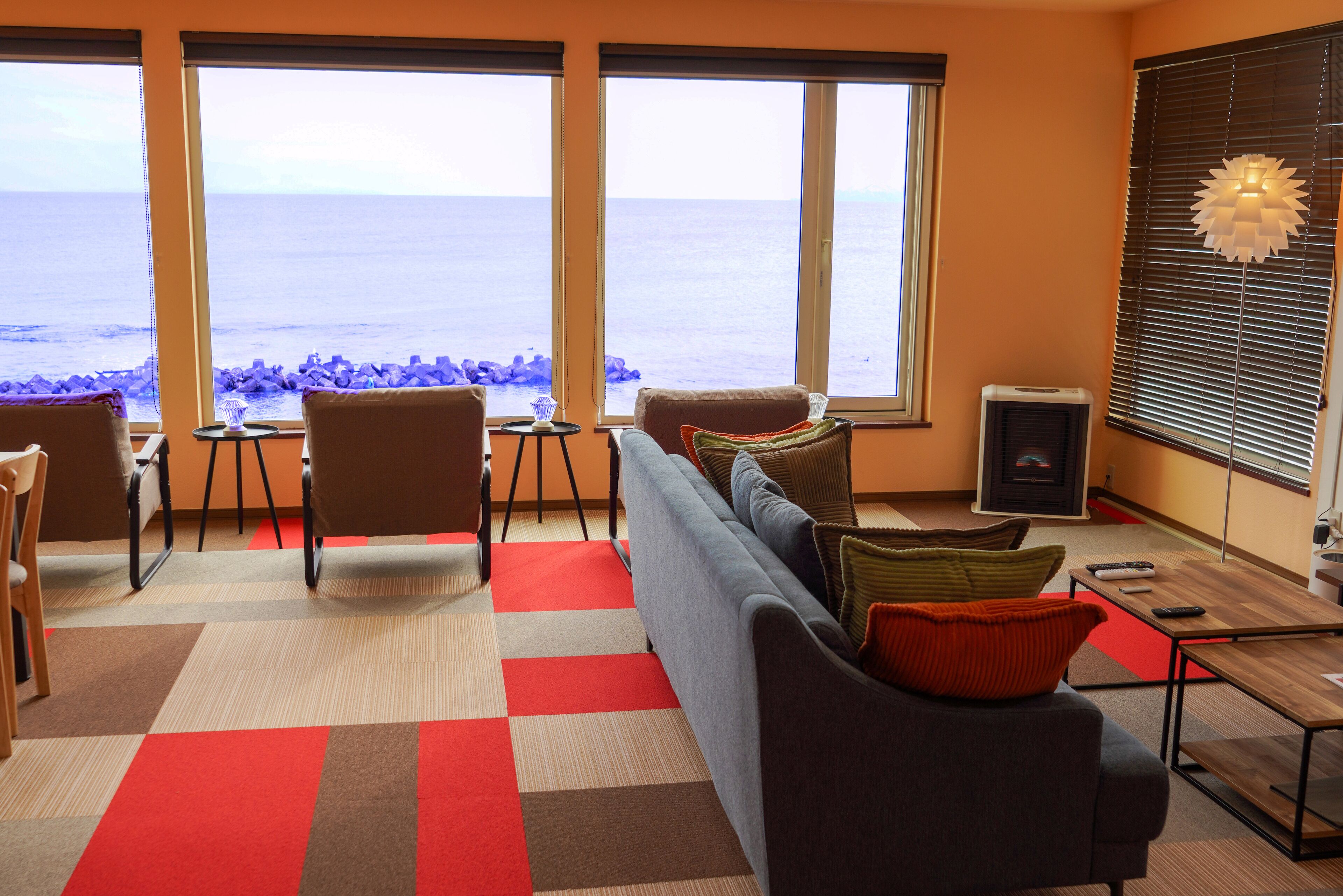 A living room with a sofa, chairs, a small table, and a view of the sea.
