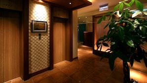 A hallway with wooden walls, a tiled floor, a waiting bar sign, and a plant. - HOTELm - Adults Only (Matsudo)