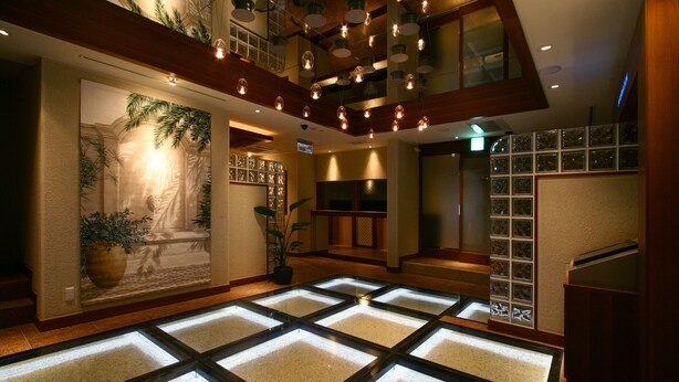 A hotel lobby with a modern design, featuring a large central area with a patterned floor, a staircase, and a wall with a decorative mural. - HOTELm - Adults Only (Matsudo)
