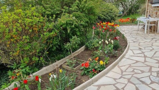 A stone pathway leading to a patio area with a table and chairs, surrounded by a garden with various plants and flowers. - Studio Indépendant Refait à Neuf (Villiers-Saint-Denis)