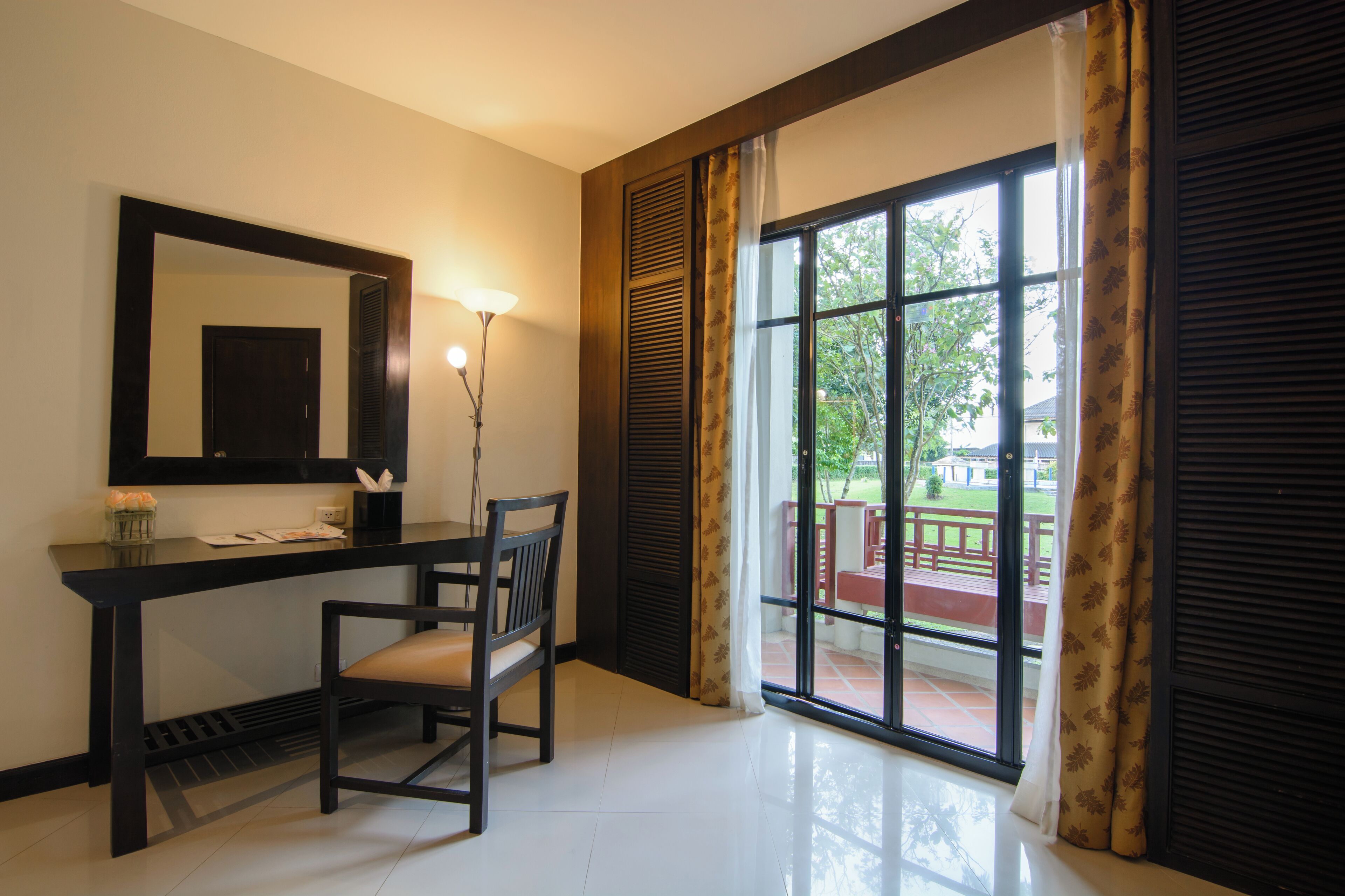 A room with a desk, chair, and a large window with curtains.