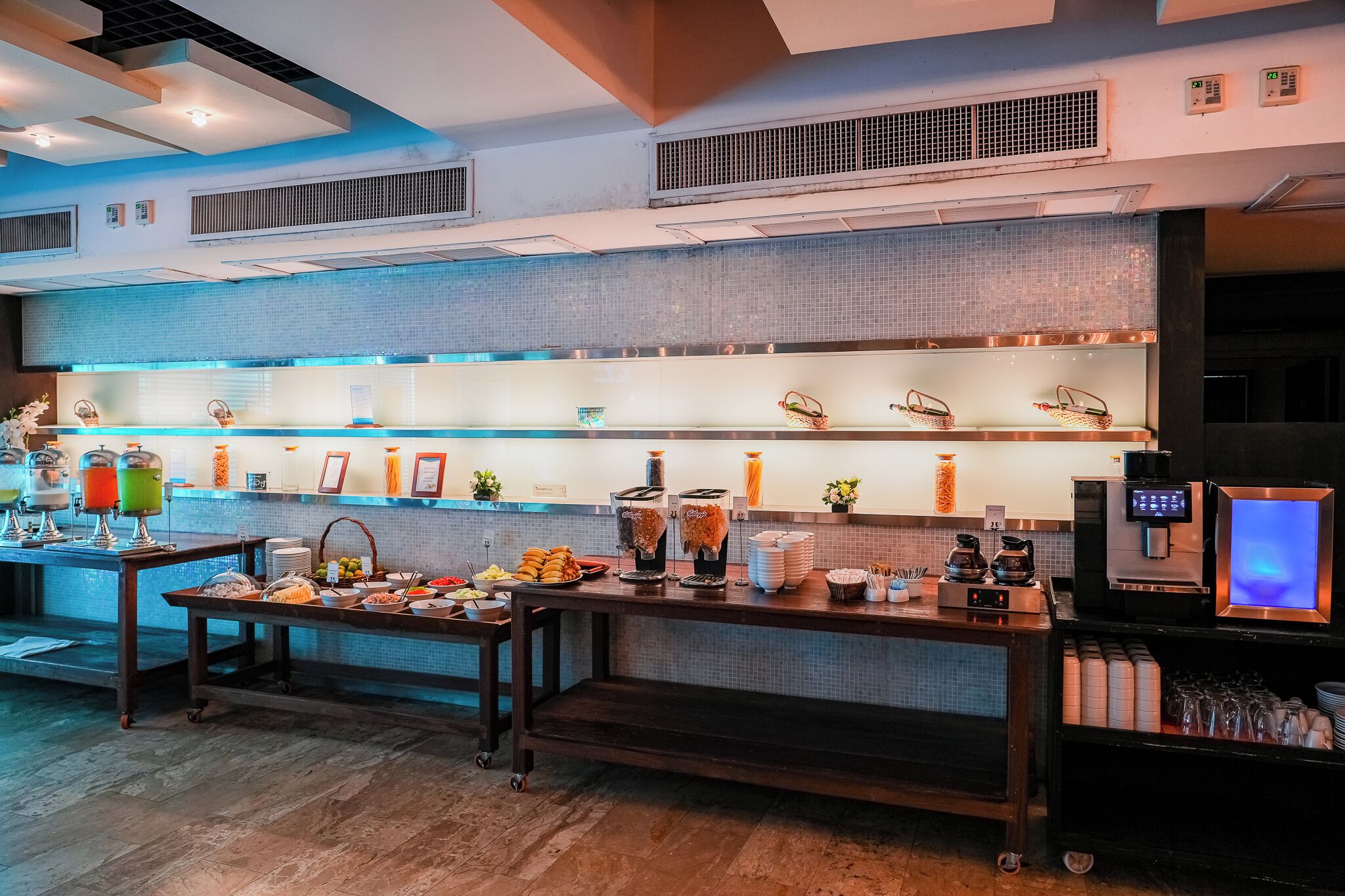 A buffet setup with various food items and beverages, a coffee machine, and a microwave.