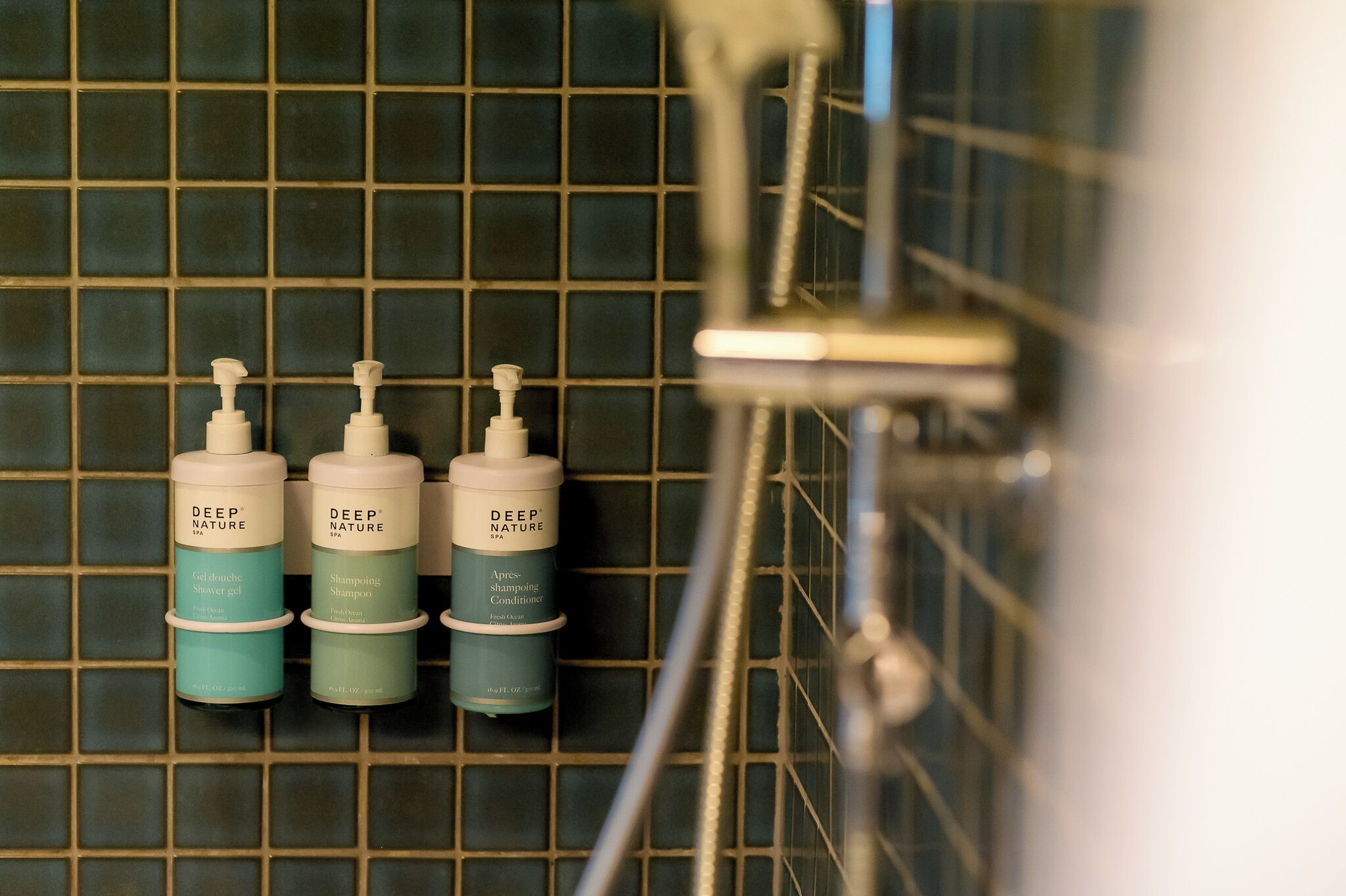 Three bottles of Deep Nature products on a tiled wall.