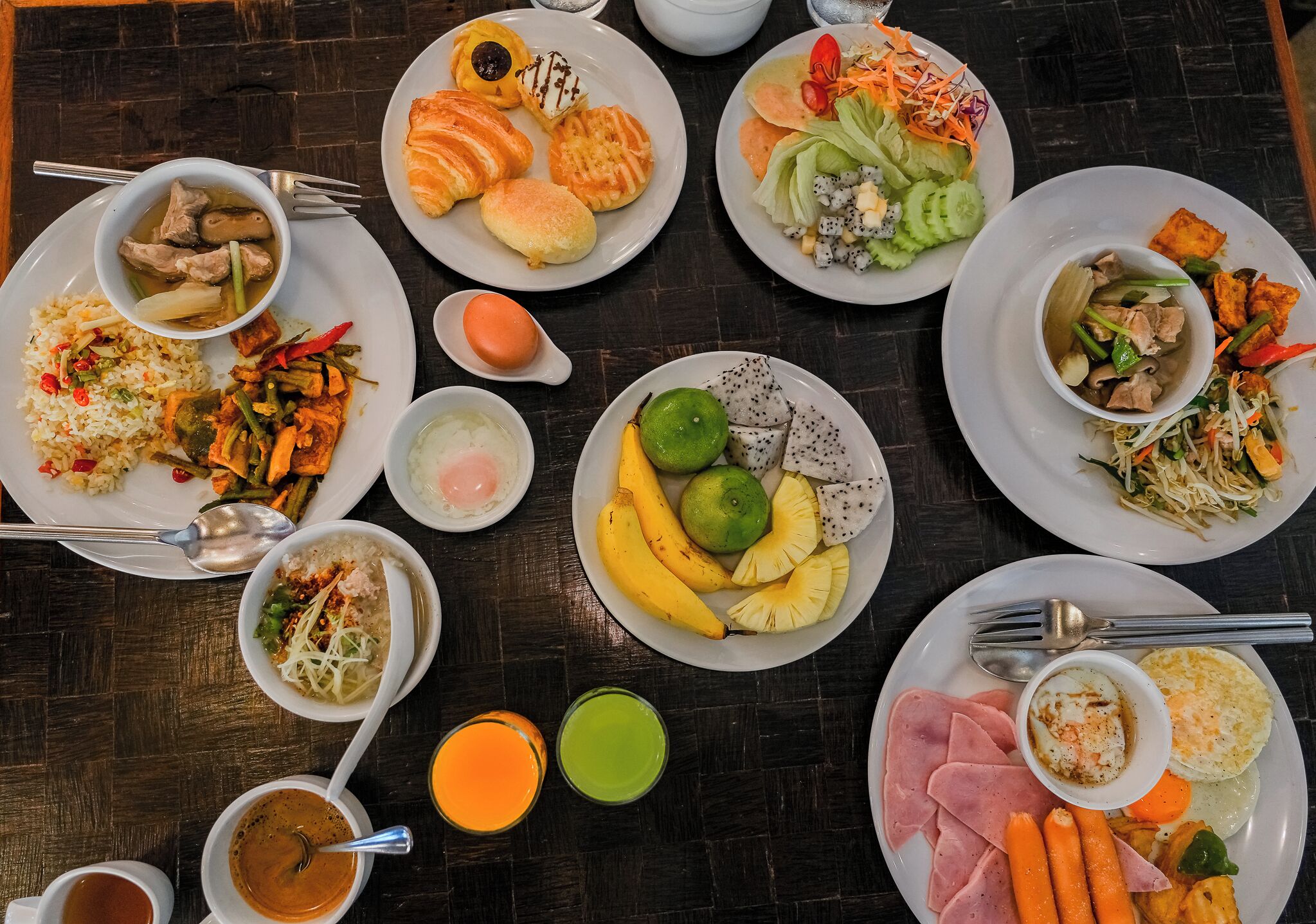 A table with various dishes including rice, vegetables, and meat, along with two glasses of juice.