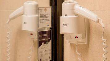 Un secador de pelo y un teléfono enchufados a un enchufe en un baño.