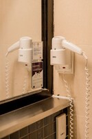Un secador de pelo y un teléfono enchufados a un enchufe en un baño.