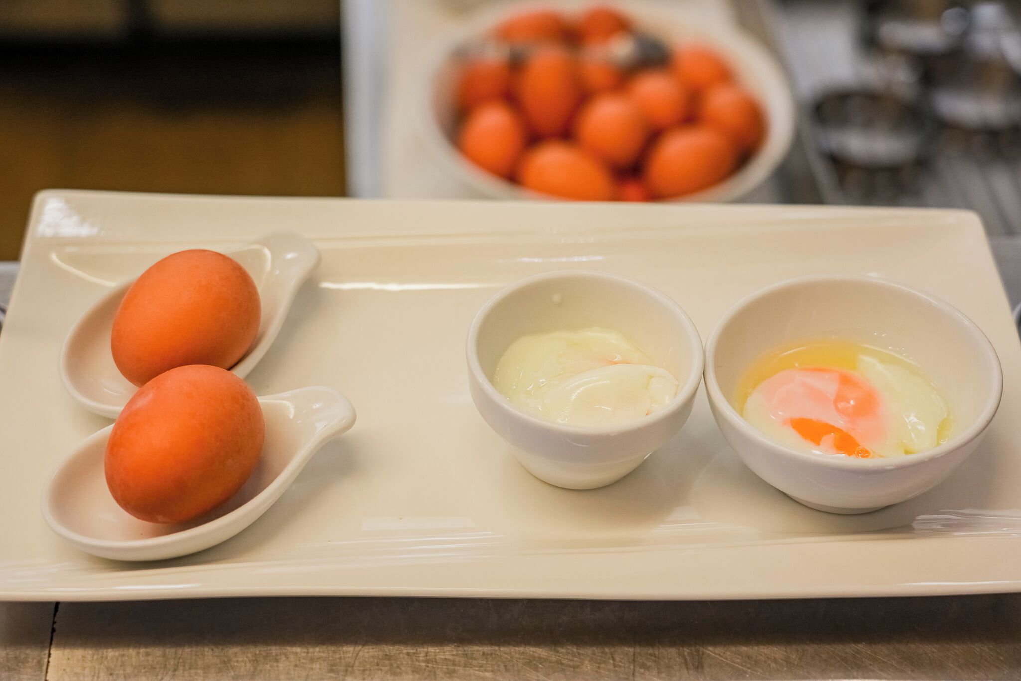 A tray with two poached eggs and two small bowls of egg yolk.