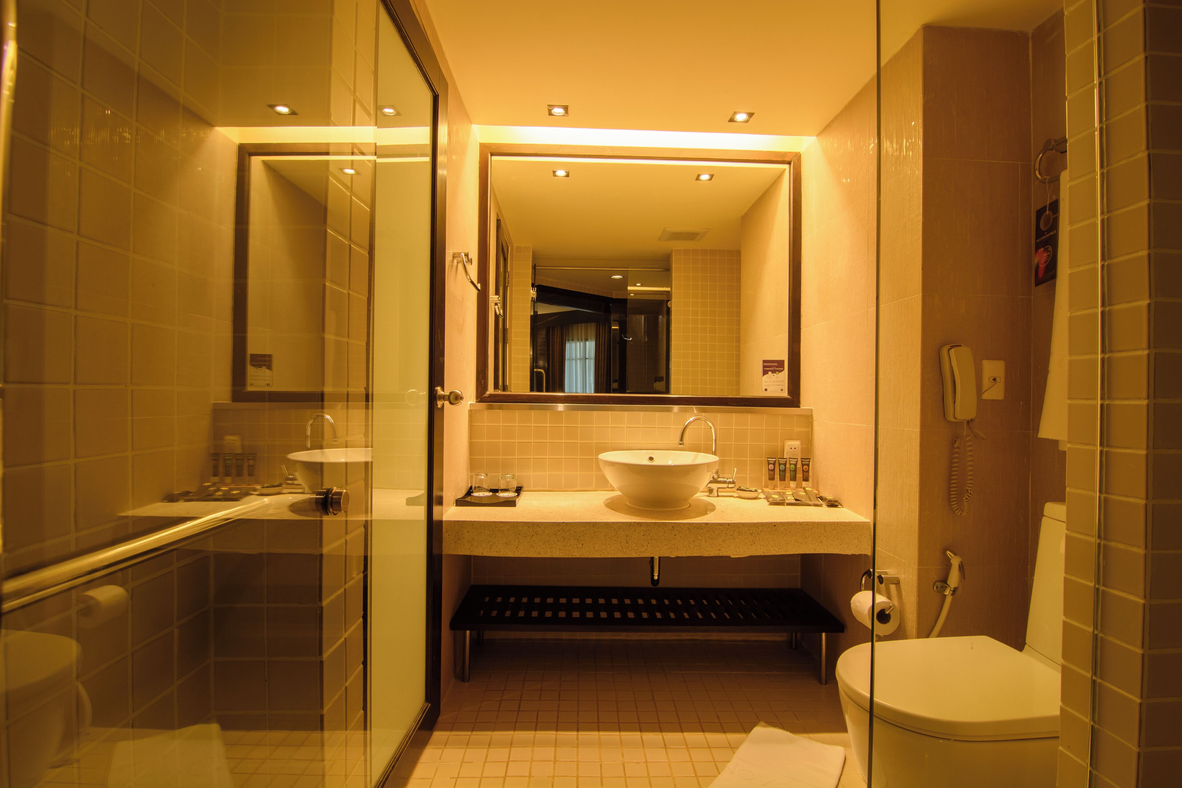 Un baño moderno con ducha de vidrio, un lavabo con espejo y un inodoro.