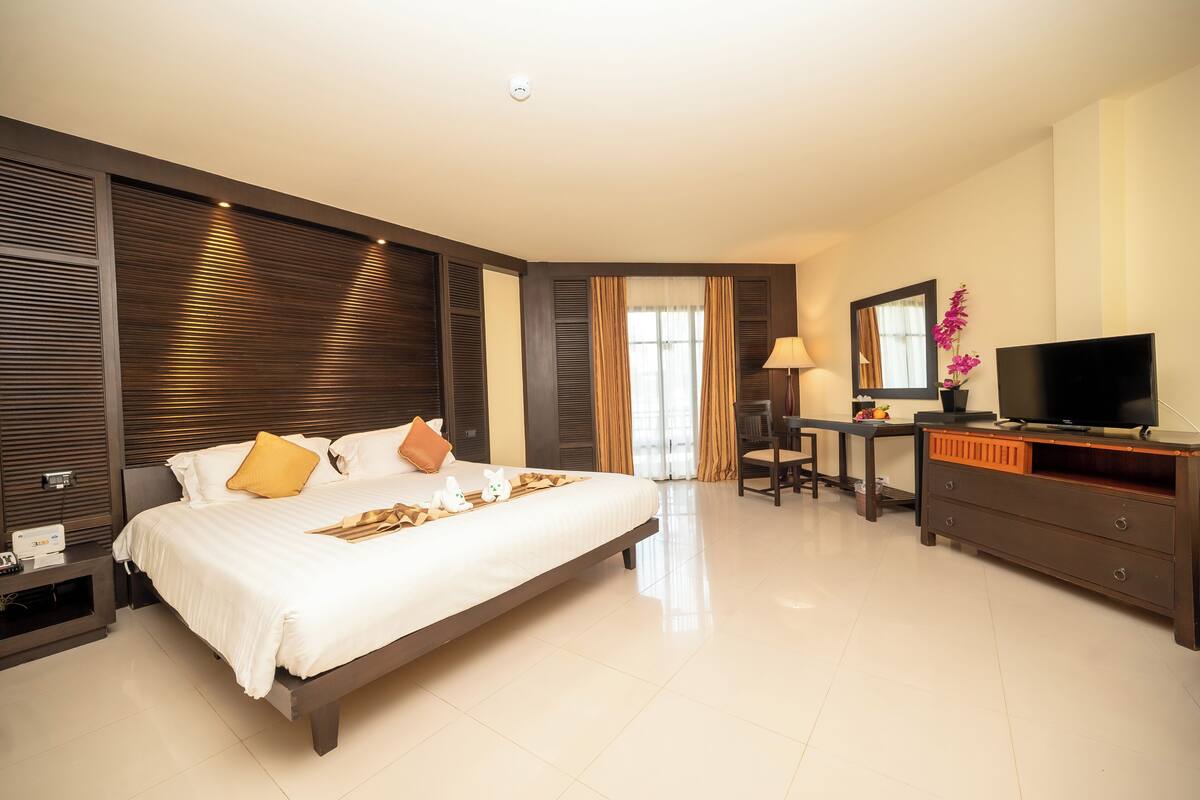 Une chambre d’hôtel avec un grand lit, un bureau, une télévision et une commode.