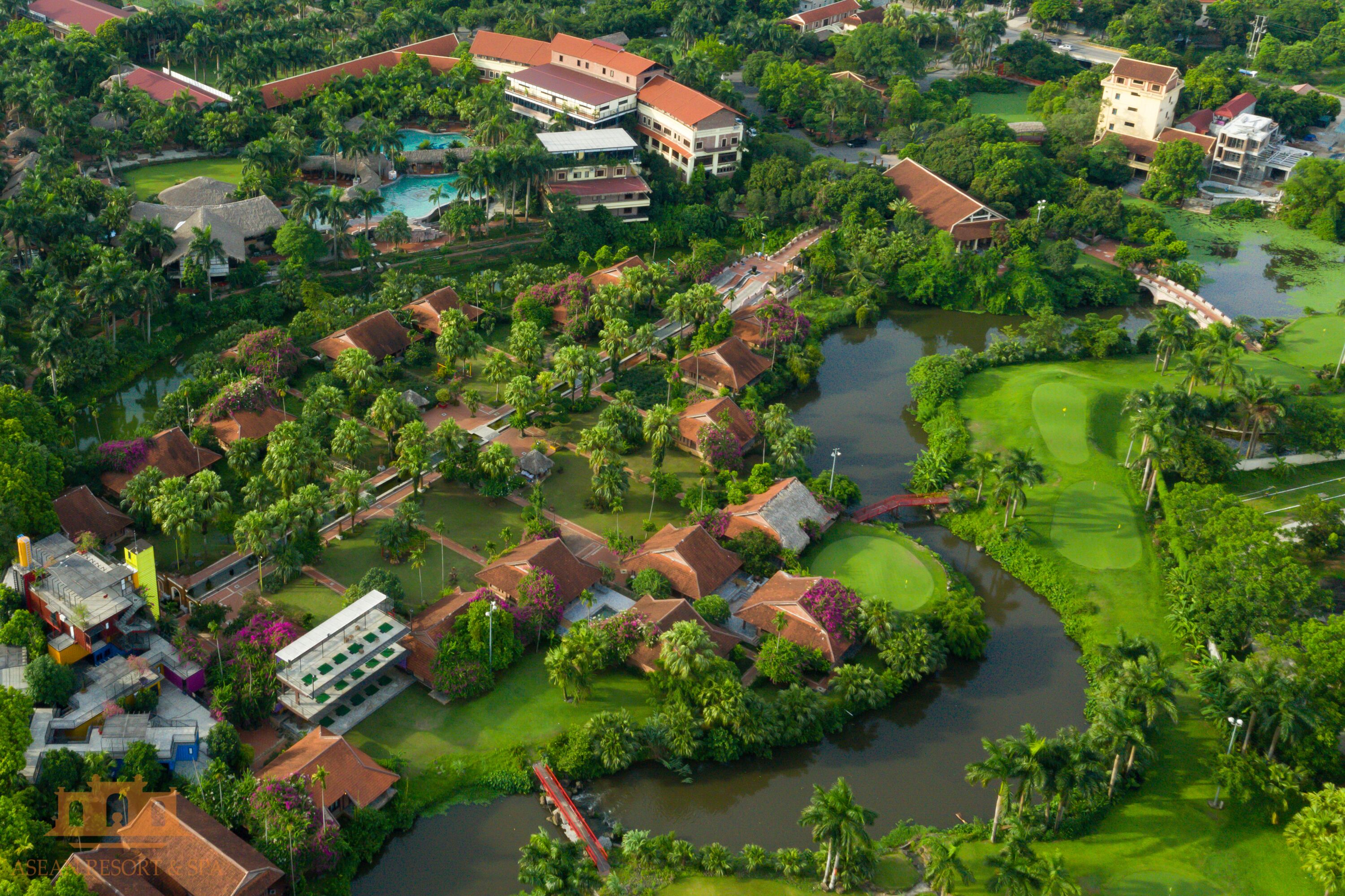 An aerial view of a resort with multiple buildings, a golf course, and a water body.