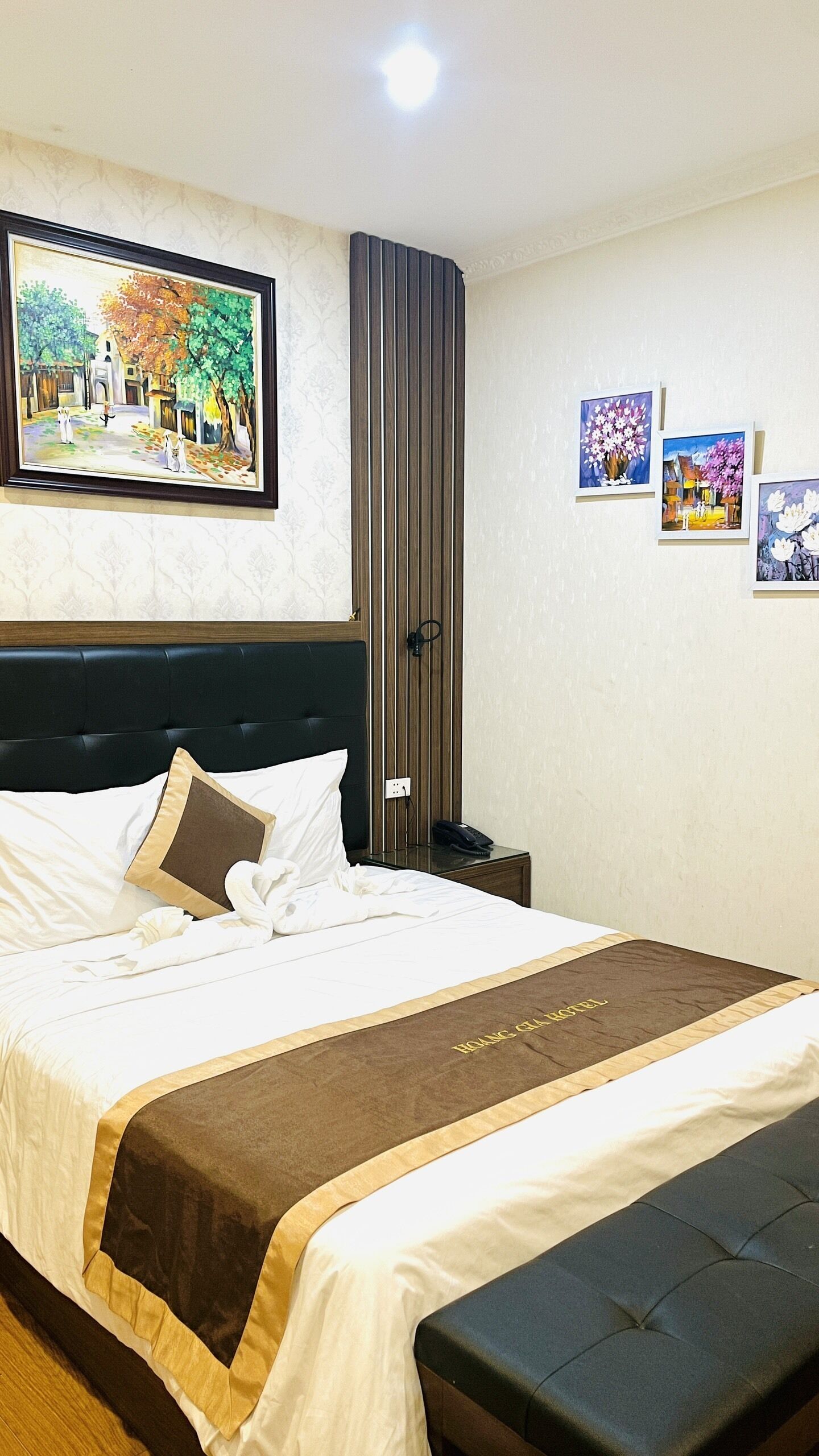 A neatly made bed with a brown accent, a headboard, and a bedside table with a phone.