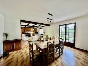 A dining area with a wooden table and chairs, a fireplace, and a view of the outdoors through a large window.