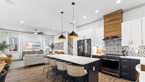 A modern kitchen with a central island, black and white backsplash, and stainless steel appliances. - Diamond Oasis | Private Pool/Spa | Arcade Games | Private Beach Access (Miramar Beach)