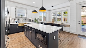 A modern kitchen with black cabinets, a white countertop, and pendant lighting. - Diamond Oasis | Private Pool/Spa | Arcade Games | Private Beach Access (Miramar Beach)