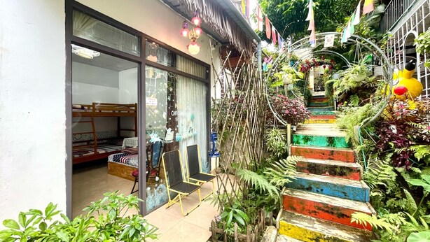 A colorful staircase leading to a building with a glass door, surrounded by greenery and plants. - Lake View Homestay (Dien Hong)