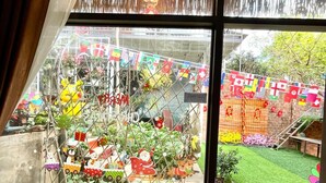 A room with a large window overlooking a garden area with various decorations and plants. - Lake View Homestay (Dien Hong)