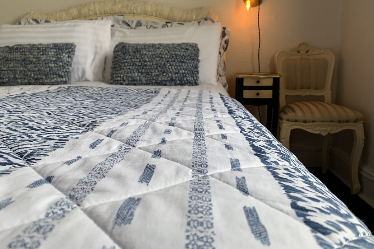 Un lit avec une couvre-lit à motifs, une table de chevet avec une lampe et une chaise.