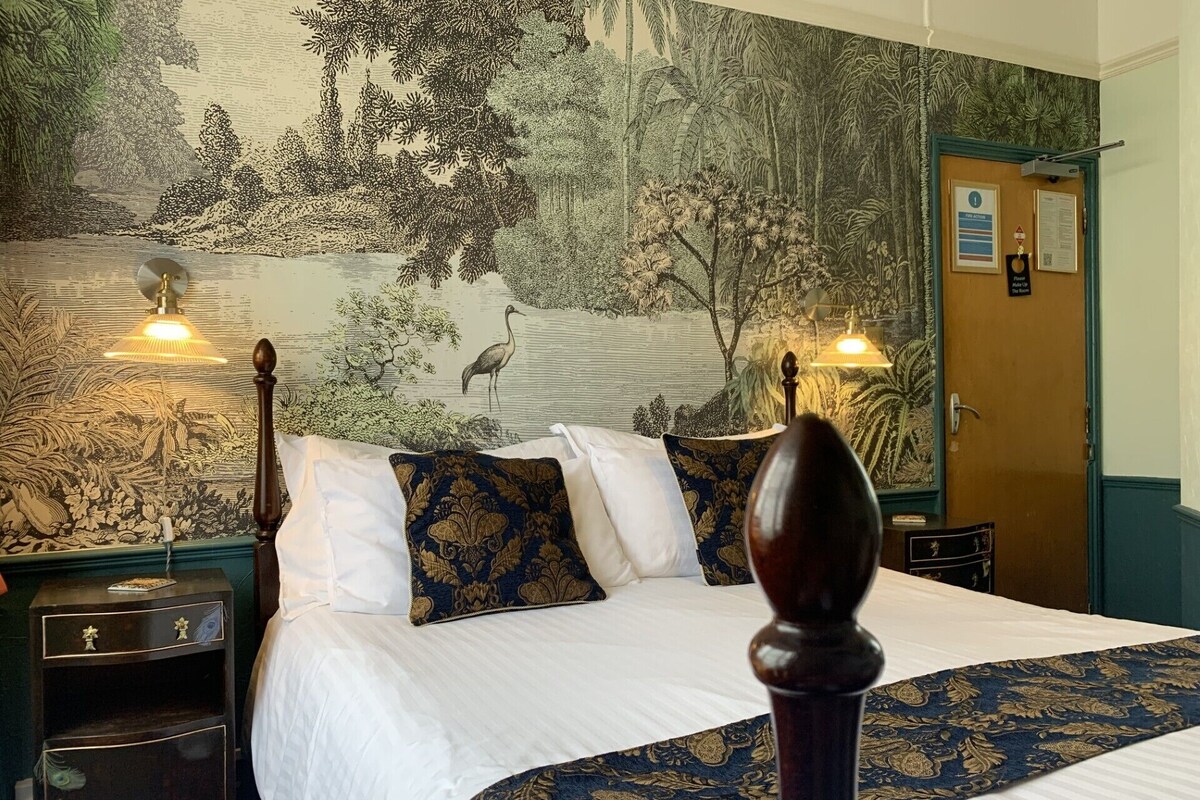 Une chambre à coucher avec une grande fresque murale, un lit à baldaquin et deux lampes de chevet.