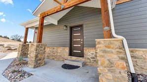 A house with a stone foundation, a wooden porch, and a dark-colored door.