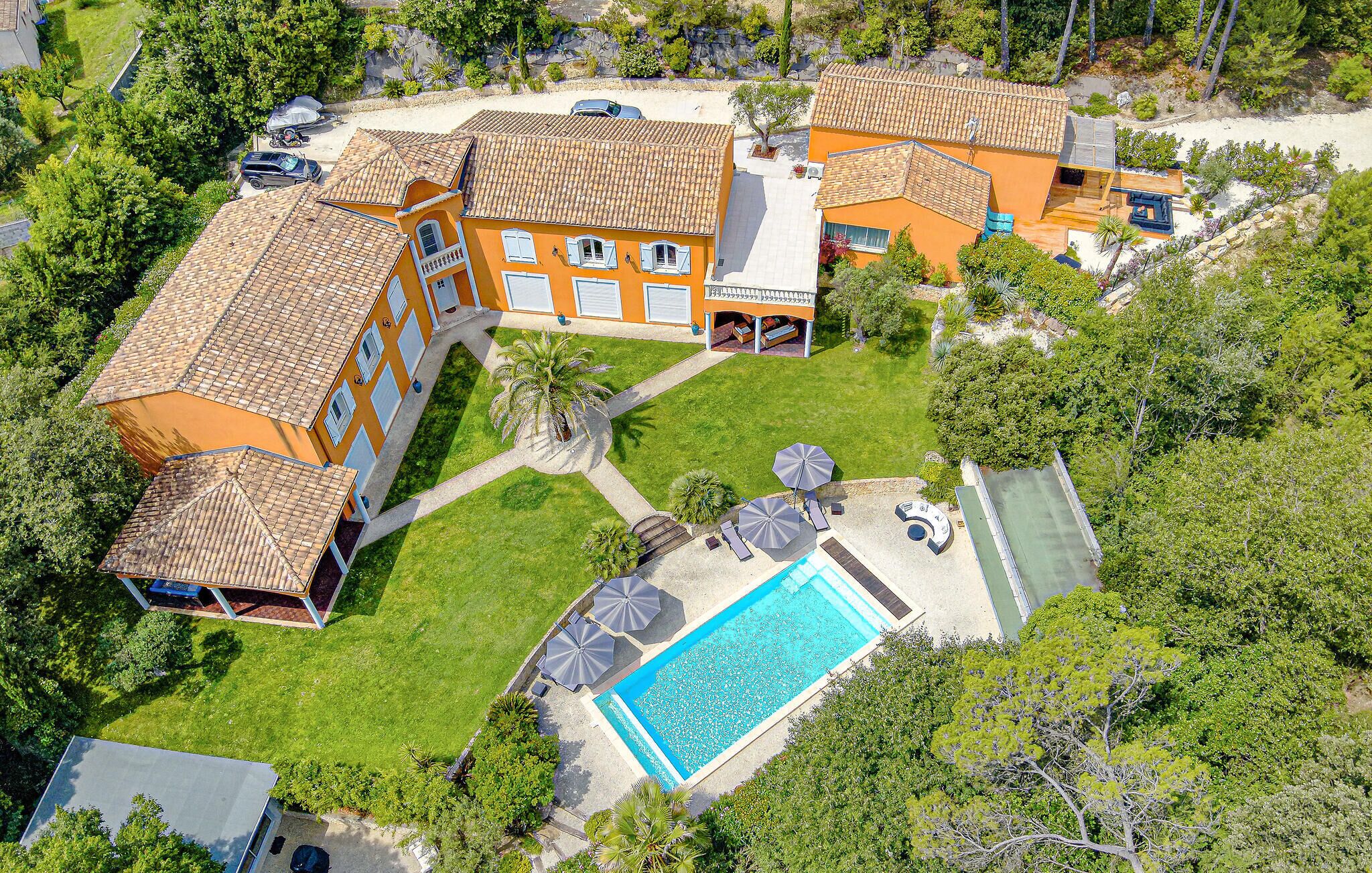 An aerial view of a residential property with a swimming pool, multiple buildings, and surrounding greenery.