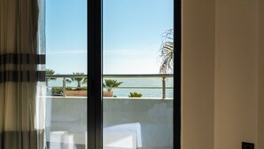 Une chambre d’hôtel avec une grande fenêtre donnant sur une piscine et la mer.