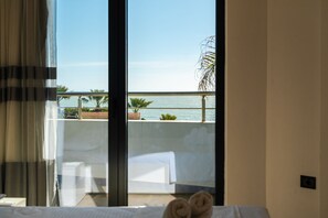 Una habitación de hotel con un ventanal grande que da a una piscina y al mar.