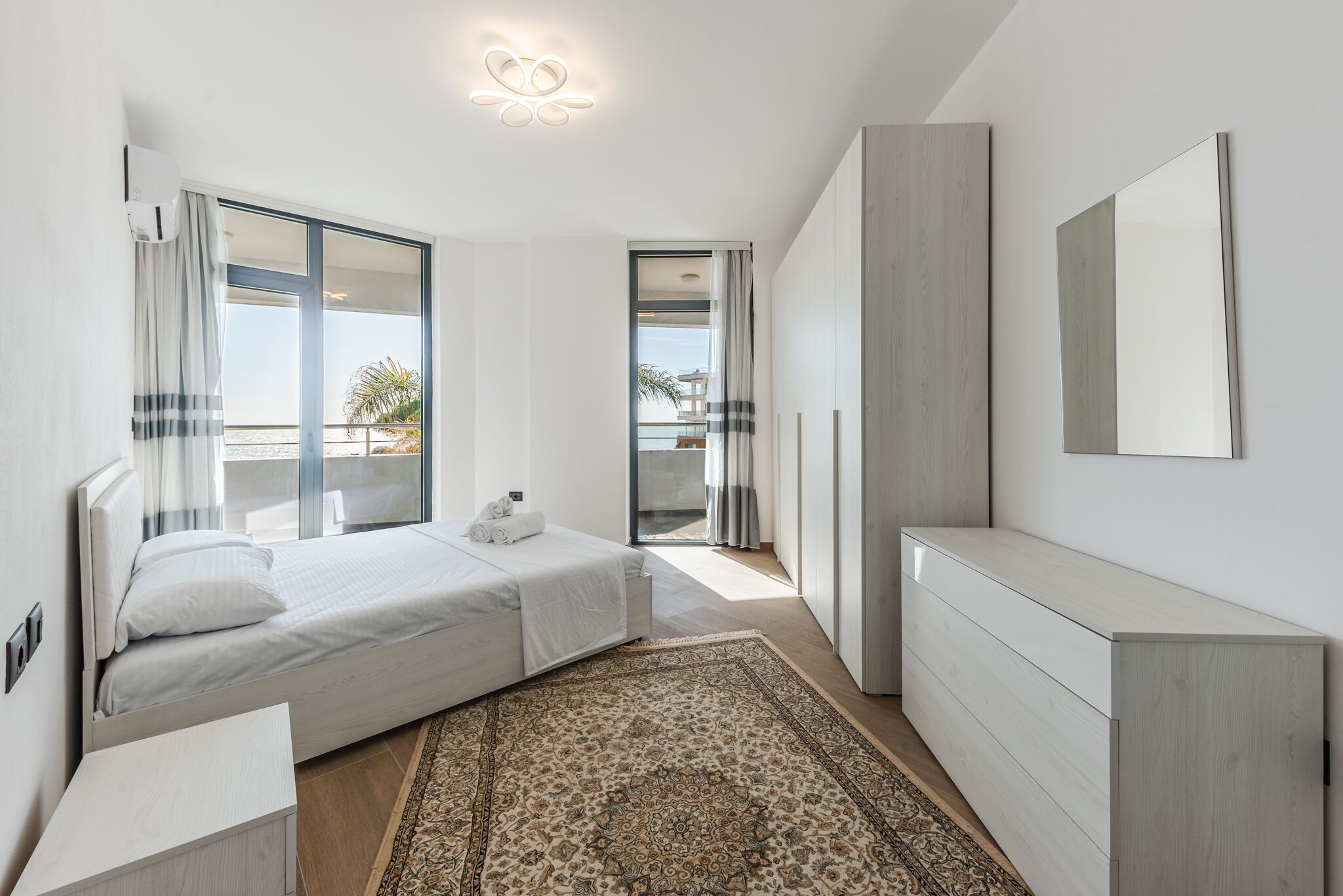Une chambre à coucher moderne avec un lit, une table de chevet et un grand miroir.