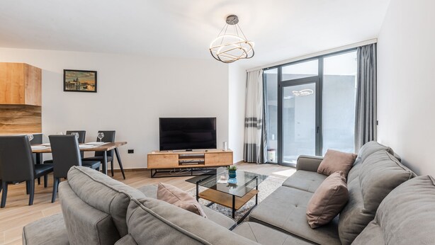 Un salon moderne comprenant un canapé, une table basse, un téléviseur et un coin repas avec des chaises et une table.