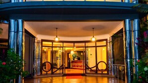 A hotel entrance with a reception desk, a red carpet, and a glass door. - Nejobugg palace hotel (Arusha)