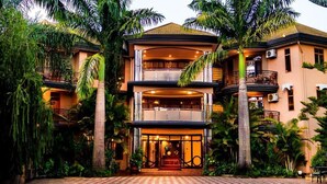 A multi-story hotel with a central entrance, balconies, and lush tropical vegetation. - Nejobugg palace hotel (Arusha)