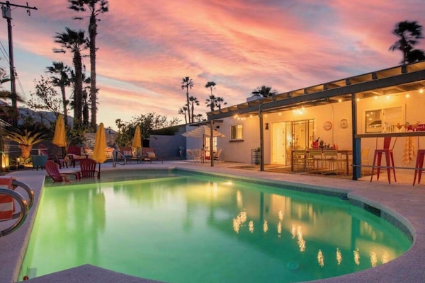 Pool and covered patio at sunset, with palm trees around the yard.