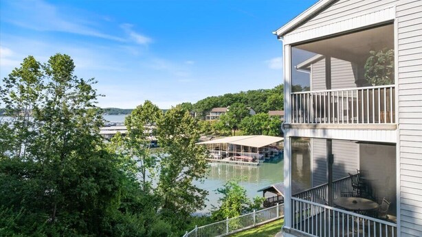 A waterfront property with a balcony overlooking a lake, surrounded by trees. - Main channel view, playground, no steps enrty (Lake Ozark)