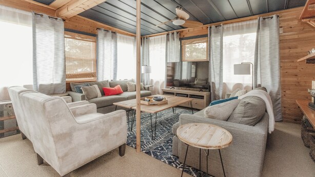 A modern living room with a sofa, armchairs, a coffee table, and a TV.